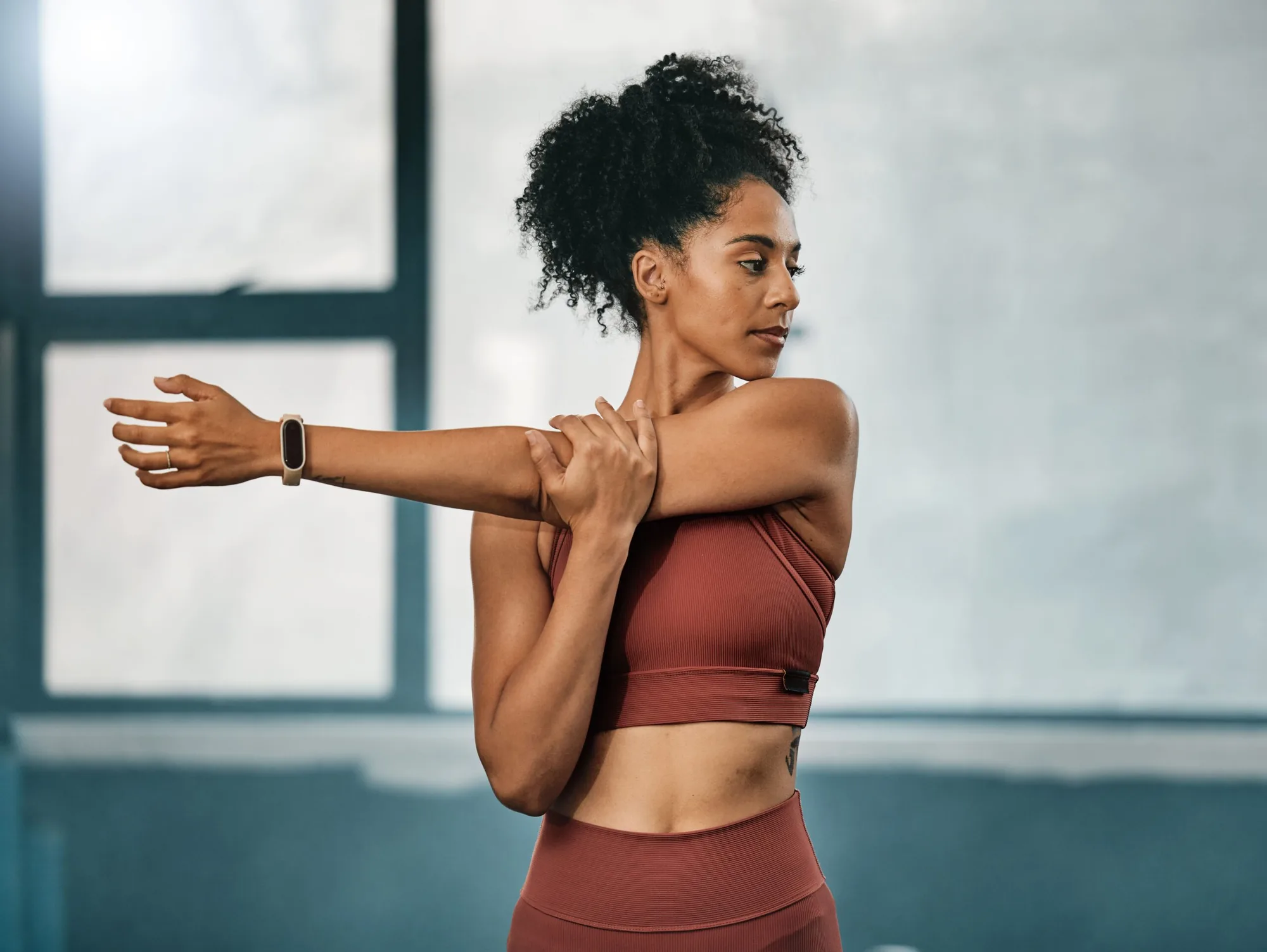 Woman stretching her arm in a bright studio